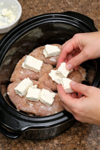 Nałóż ser śmietankowy na surowe piersi z kurczaka i dodaj 2 podstawowe produkty spożywcze do wolnowaru, aby uzyskać kremowy obiad, na który mam ochotę co tydzień